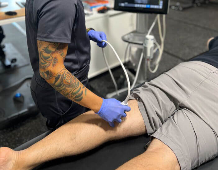 Dr Falconi using an ultrasound machine on a patient's leg