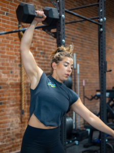 Woman holds heavy hand barbell above her head